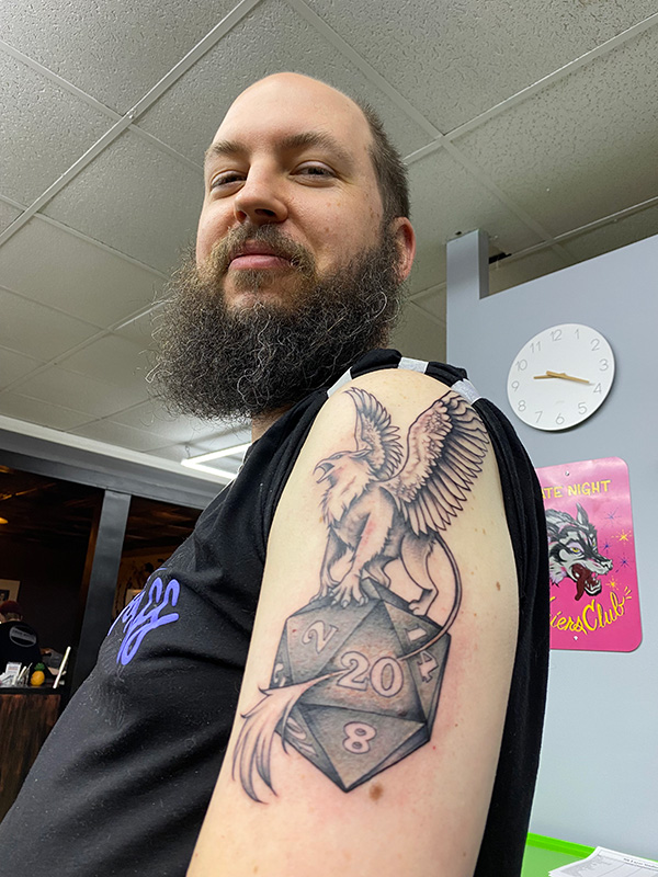 Photo of my tattoo of a gryphon perched on a d20